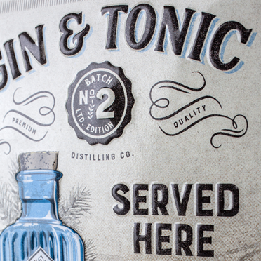 Decorative sign with 'Gin & Tonic Served Here' text and a blue bottle illustration on a metallic background.